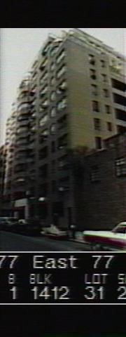 Low-resolution colour tax photograph of a pale brick apartment house stepping back at its upper floors, with dark recessed balconies, cars parked along the street below, and a caption bar reading 177 East 77, block 1412, lot 31.